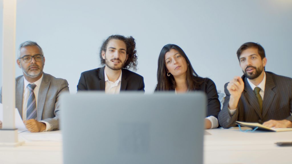 Diverse team of professionals in a meeting discussing with focus on video conferencing setup.
